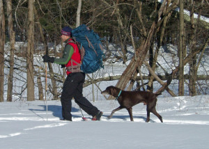 In winter, a BIG backpack like this Osprey Argon 110 is needed to carry all your gear. Not nearly so useful is Chester, the dog, who is about to step on the back of his master’s snowshoe . . .